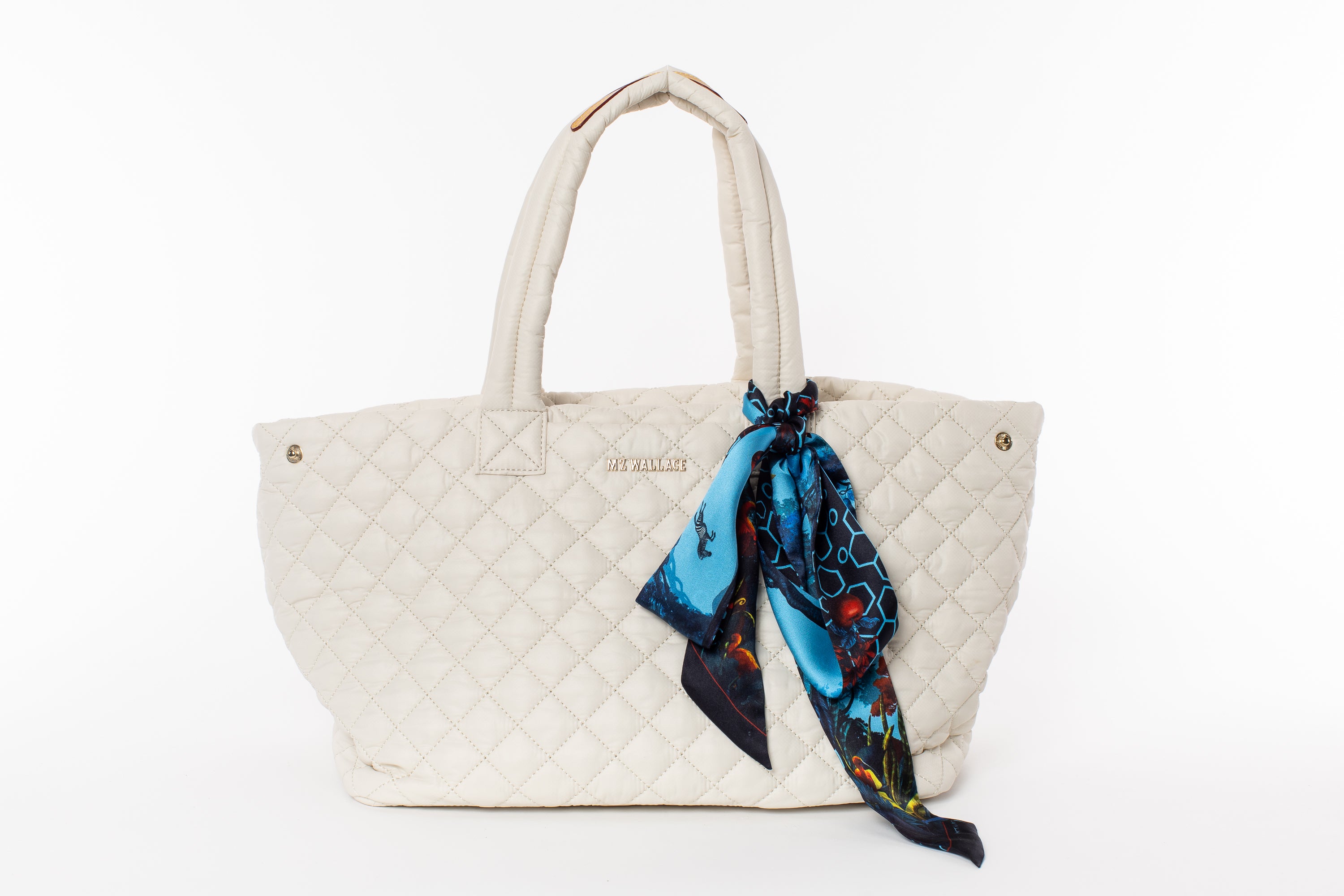 Quilted tote bag with a colorful scarf draped over it on a white background